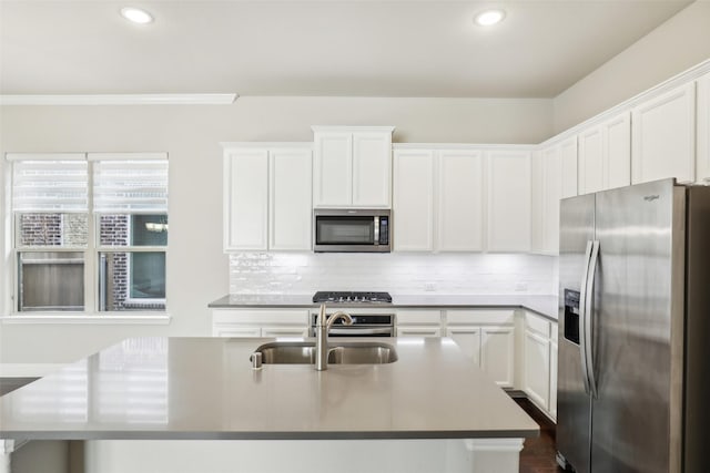 kitchen featuring appliances with stainless steel finishes, white cabinets, a sink, and backsplash