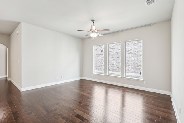 unfurnished room with ceiling fan, visible vents, arched walkways, and dark wood finished floors