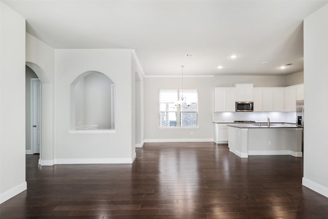 kitchen with open floor plan, stainless steel microwave, dark wood-style floors, and baseboards