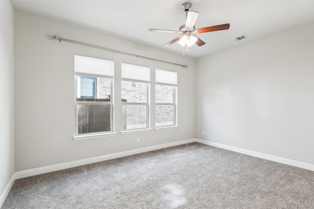 carpeted spare room featuring a ceiling fan, visible vents, and baseboards