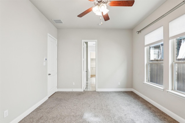 unfurnished room with carpet, visible vents, ceiling fan, and baseboards