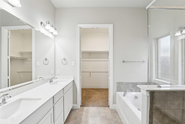 full bathroom featuring a garden tub, a sink, a walk in closet, and tile patterned floors