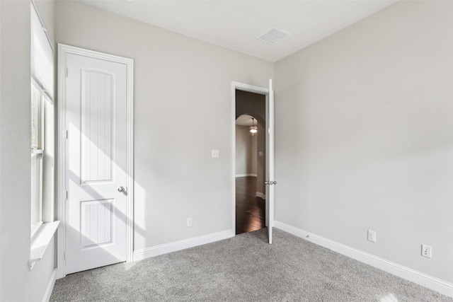 unfurnished bedroom with carpet floors, visible vents, and baseboards