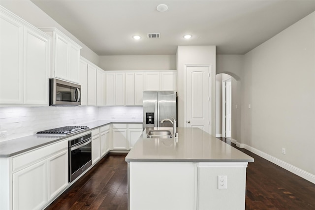 kitchen featuring tasteful backsplash, visible vents, arched walkways, appliances with stainless steel finishes, and a sink