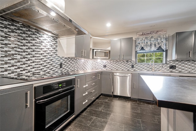 kitchen with stainless steel appliances, gray cabinets, wall chimney range hood, and tasteful backsplash