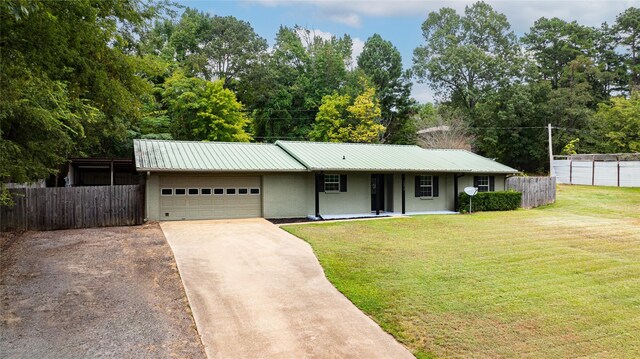 ranch-style home featuring an attached garage, fence, metal roof, and a front yard