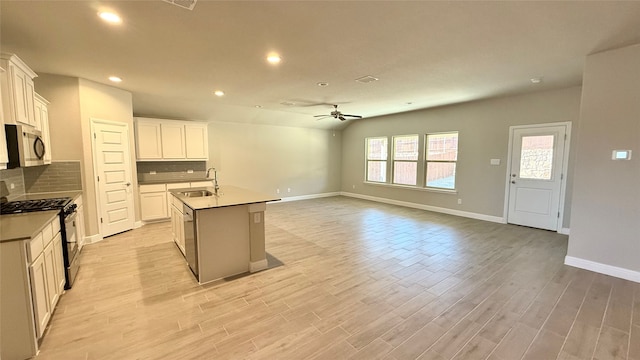 kitchen featuring appliances with stainless steel finishes, a sink, light wood-style flooring, and tasteful backsplash