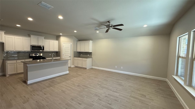 kitchen featuring appliances with stainless steel finishes, dark countertops, visible vents, and tasteful backsplash