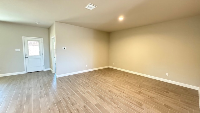 empty room featuring baseboards, visible vents, and light wood finished floors