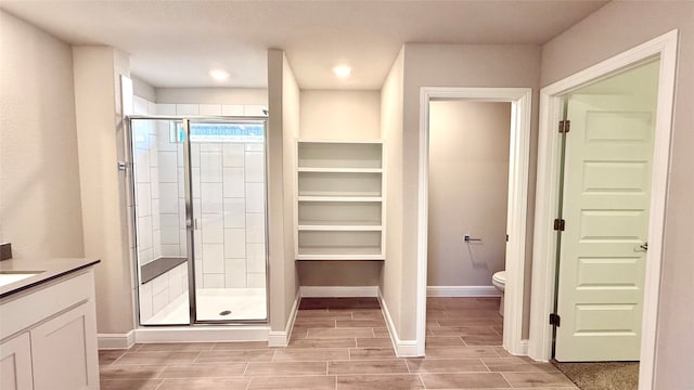 full bath featuring toilet, vanity, baseboards, wood tiled floor, and a stall shower