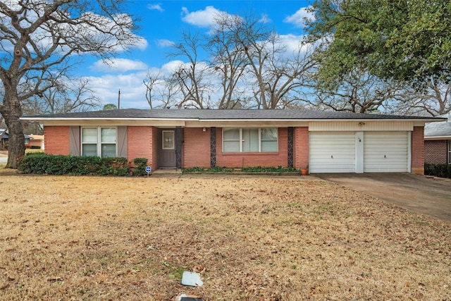 ranch-style home featuring concrete driveway, brick siding, an attached garage, and a front yard