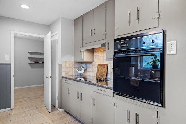 kitchen with dark countertops, light wood-style flooring, backsplash, black appliances, and baseboards