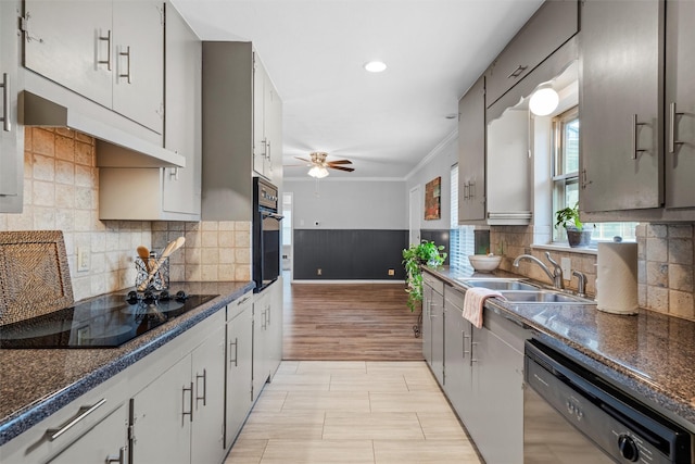 kitchen featuring a sink, a ceiling fan, wainscoting, black appliances, and crown molding