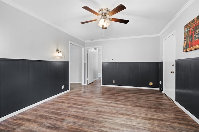 unfurnished room with a wainscoted wall, ornamental molding, and wood finished floors