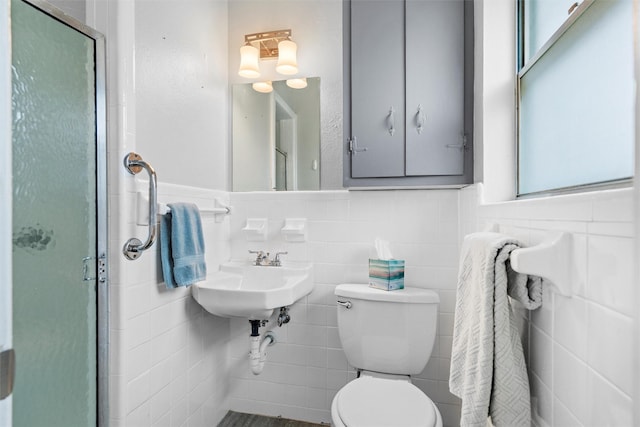 full bathroom with tile walls, a sink, a shower stall, and toilet