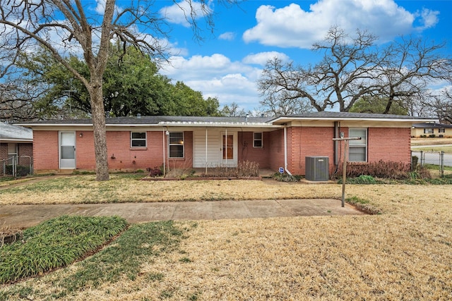 ranch-style house with brick siding, fence, a front lawn, and central air condition unit