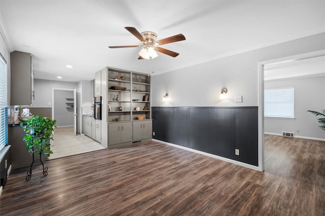 interior space featuring ceiling fan, wainscoting, wood finished floors, and visible vents