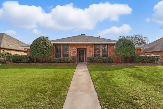 view of front facade featuring brick siding, roof with shingles, and a front yard