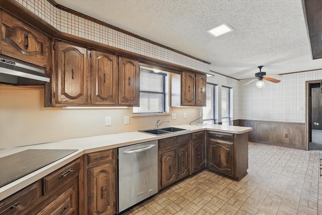 kitchen featuring a wainscoted wall, a sink, light countertops, stainless steel dishwasher, and brick patterned floor