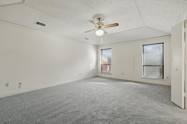 carpeted spare room featuring a textured ceiling, visible vents, vaulted ceiling, and a ceiling fan