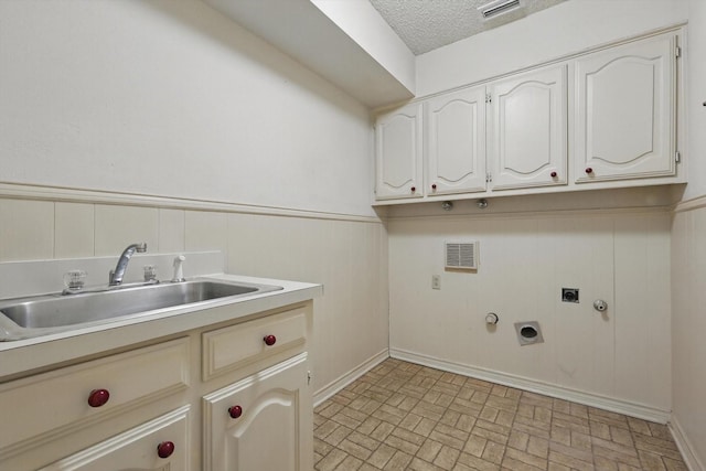 laundry area featuring hookup for an electric dryer, hookup for a gas dryer, a sink, wainscoting, and cabinet space