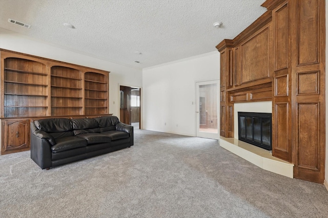 living room featuring a textured ceiling, visible vents, carpet flooring, and a glass covered fireplace