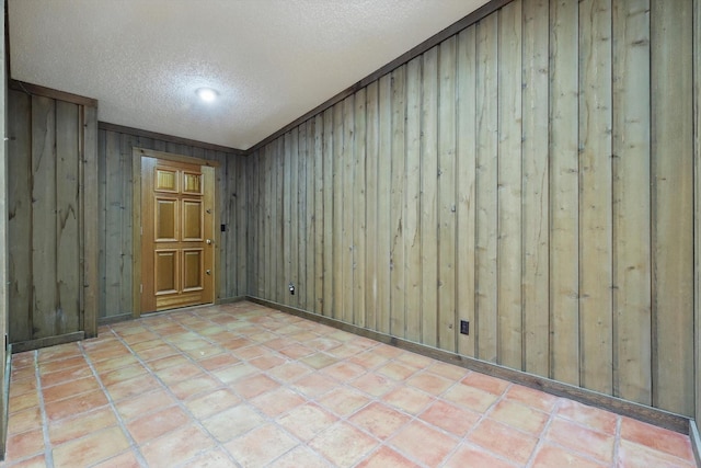 tiled spare room featuring a textured ceiling and wooden walls