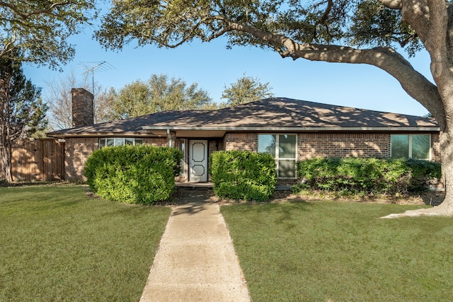 ranch-style home featuring a front yard, a chimney, fence, and brick siding