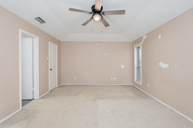 unfurnished room featuring baseboards, visible vents, light colored carpet, ceiling fan, and a textured ceiling