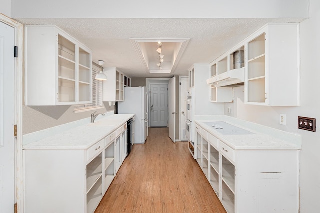 kitchen featuring white appliances, light wood finished floors, a raised ceiling, a textured ceiling, and open shelves