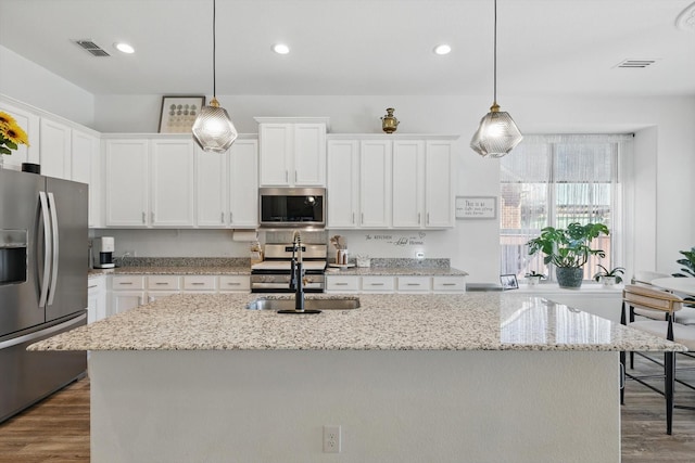 kitchen featuring an island with sink, appliances with stainless steel finishes, white cabinets, and a sink