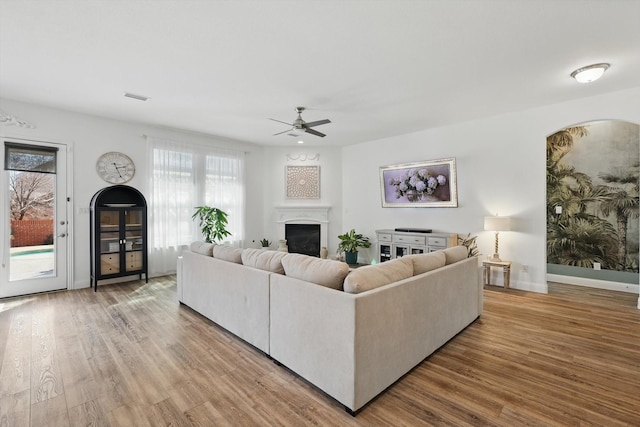 living room featuring baseboards, a fireplace, visible vents, and wood finished floors