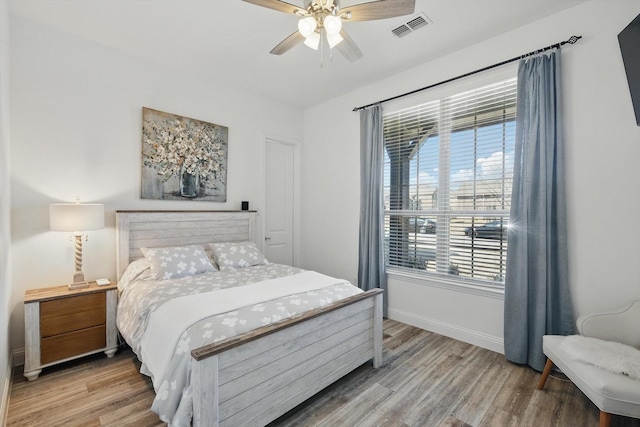 bedroom with a ceiling fan, baseboards, visible vents, and wood finished floors