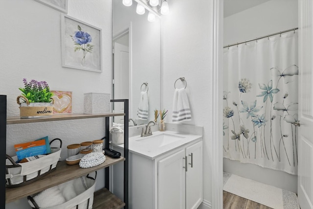 full bathroom featuring a textured wall, vanity, and wood finished floors