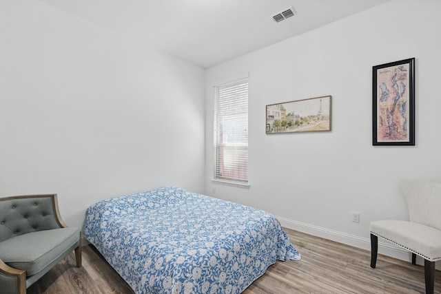 bedroom featuring visible vents, baseboards, and wood finished floors