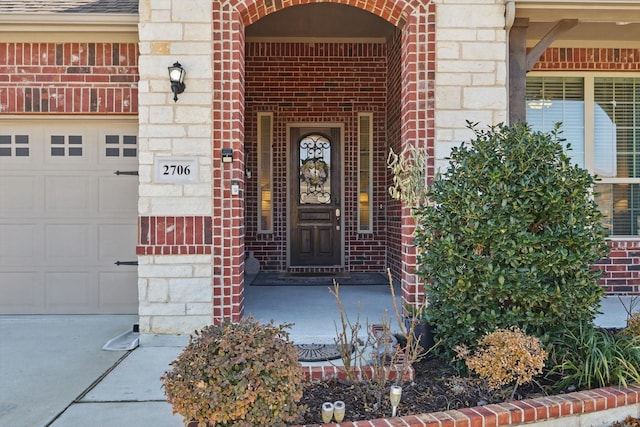 entrance to property featuring stone siding, brick siding, an attached garage, and roof with shingles