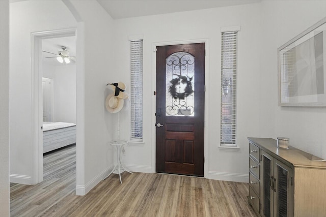 entrance foyer with light wood-type flooring, baseboards, and arched walkways