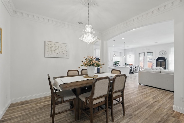 dining room featuring a chandelier, baseboards, and wood finished floors