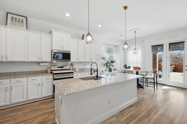 kitchen with stainless steel appliances, light wood-style floors, white cabinets, and a sink