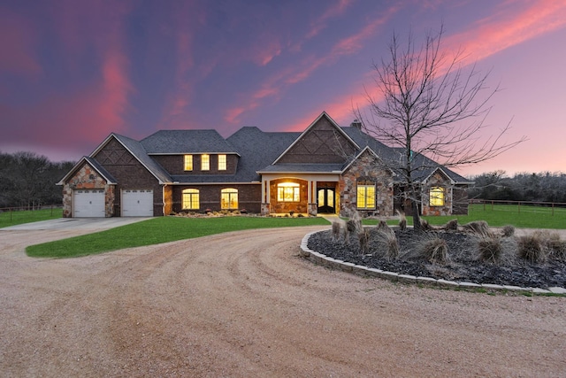 view of front facade featuring a yard, fence, a garage, stone siding, and driveway