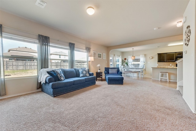 carpeted living area with baseboards, visible vents, and a wealth of natural light