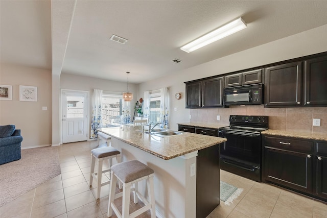 kitchen with visible vents, decorative backsplash, a sink, black appliances, and a kitchen bar