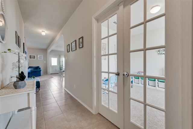 corridor with light tile patterned floors, french doors, visible vents, and baseboards