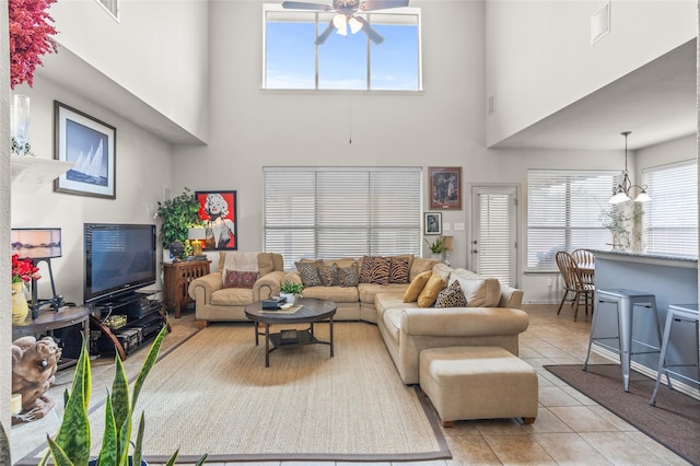 living area with light tile patterned floors, a high ceiling, visible vents, and a ceiling fan