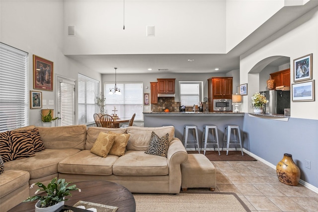 living area featuring a high ceiling, light tile patterned flooring, recessed lighting, and baseboards