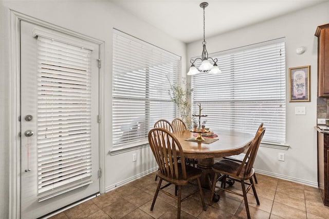 dining room featuring baseboards, light tile patterned flooring, and a notable chandelier