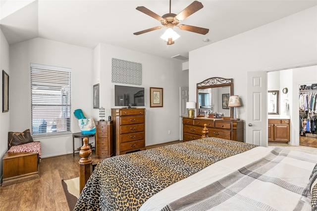 bedroom featuring lofted ceiling, wood finished floors, visible vents, a ceiling fan, and a spacious closet