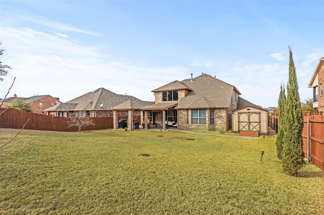 back of property with a lawn, a patio, a fenced backyard, an outbuilding, and a storage unit