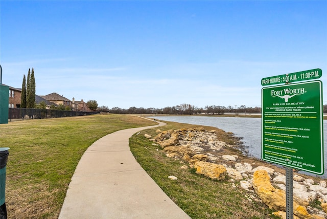 view of home's community featuring a lawn, a water view, and fence