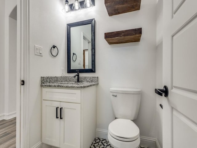 bathroom with vanity, toilet, and baseboards